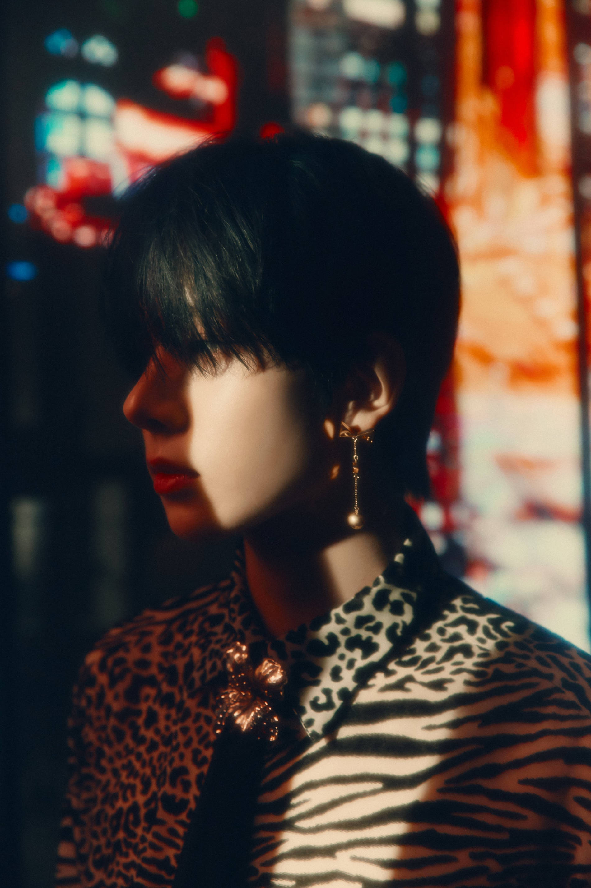 Kpop Aesthetic 桌布 壁紙 — 一個穿著豹紋和斑馬紋服裝的人，在充滿活力的散景照明城市背景下沉思地凝視著。