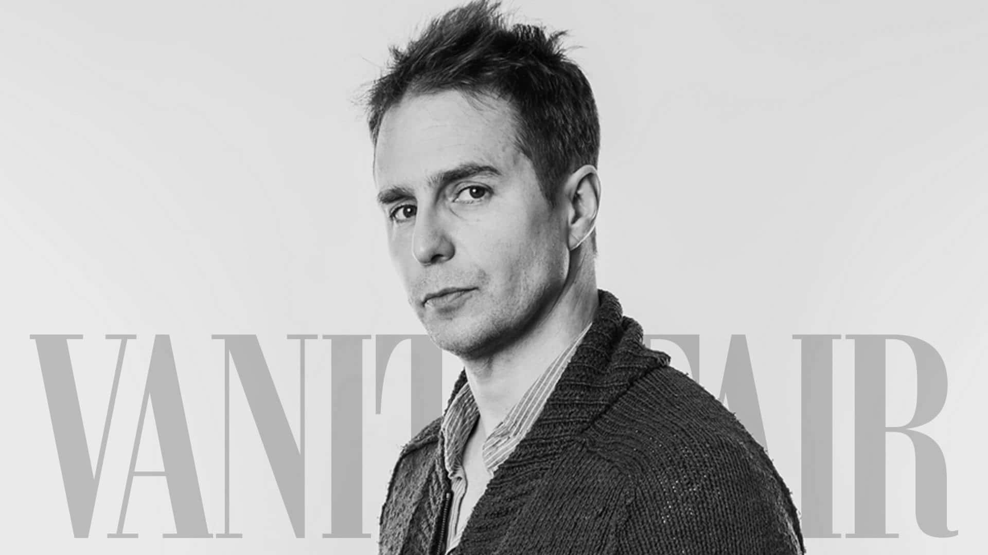 攝影 桌布 壁紙 — 一個穿著質感開襟衫的男人在純色背景上的黑白肖像，帶有 'VANITY FAIR' 文字疊加。
