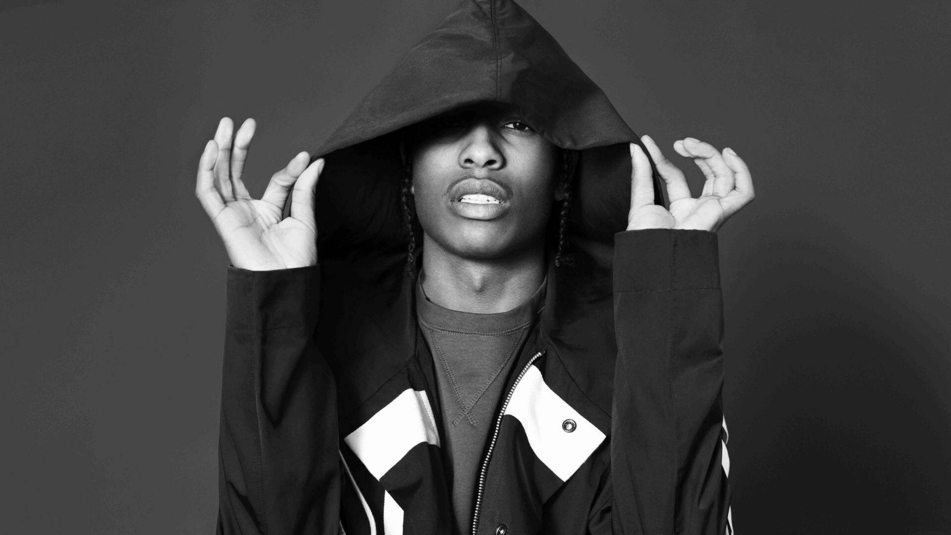 rocky 桌布 壁紙 — 一個穿著連帽外套的人拉起帽子，在深灰色背景上露出銳利的眼睛和張開的嘴巴。
