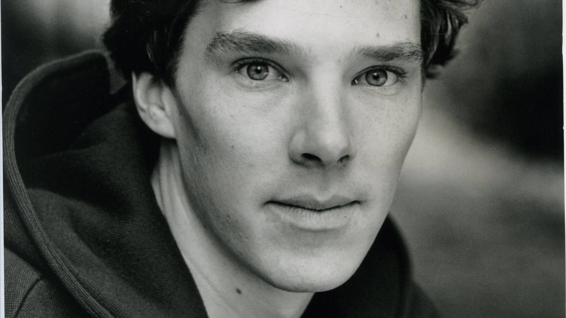 benedict 桌布 壁紙 — 一個穿著連帽衫、眼神銳利、黑髮男子的黑白特寫肖像。