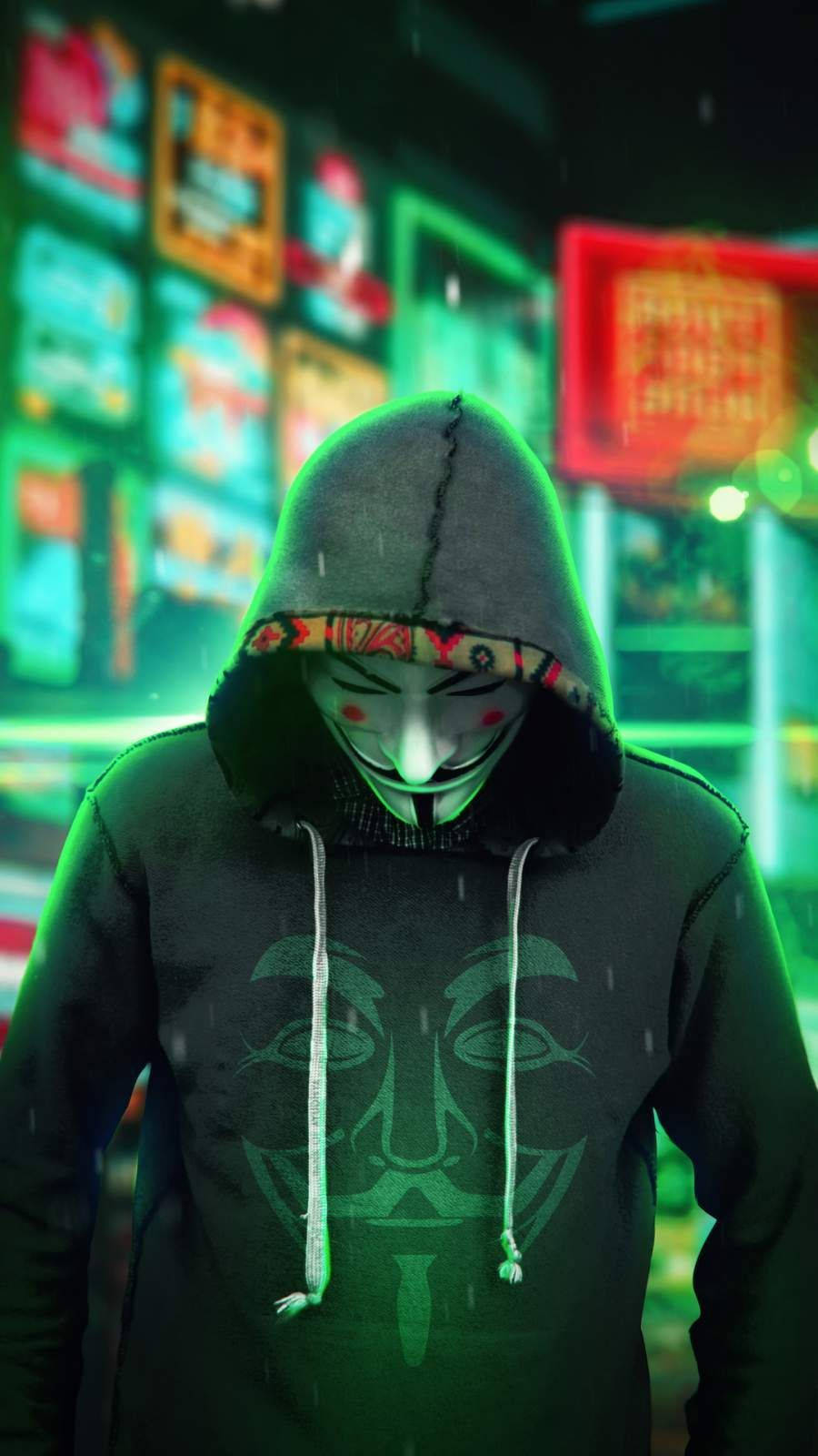 詭異的GIF 桌布 壁紙 — 一個穿著連帽衫和蓋伊·福克斯面具的人站在雨濕的霓虹燈城市街道上，街道閃爍著綠色和紅色的燈光。