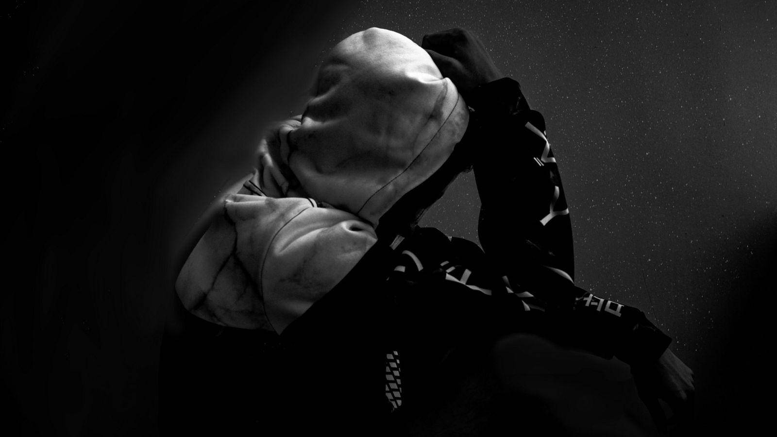 Alone Boy 桌布 壁紙 — 一個穿著連帽衫的人將帽子拉過臉部，場景昏暗、黑白、充滿情緒。
