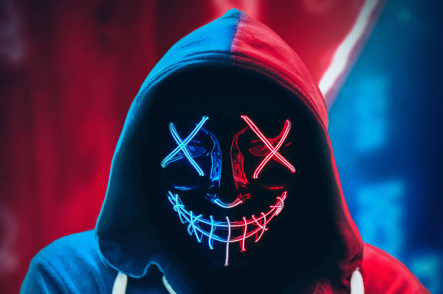 hacker 3d 桌布 壁紙 — 一個穿著連帽衫的人戴著發光面具，面具上有藍色和紅色的霓虹X眼睛和縫合的笑容，背景是鮮豔的紅色和藍色。