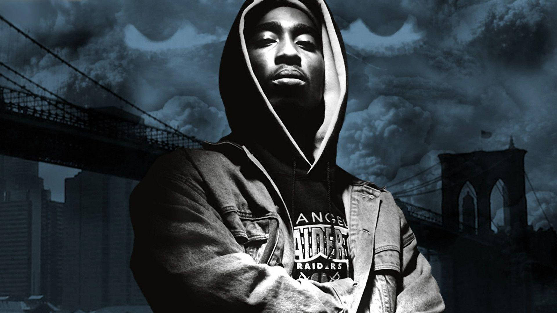 tupac 桌布 壁紙 — 一個穿著連帽衫的男人在暴風雨的天空下，以布魯克林大橋為背景，自信地站在黑暗的城市背景前。