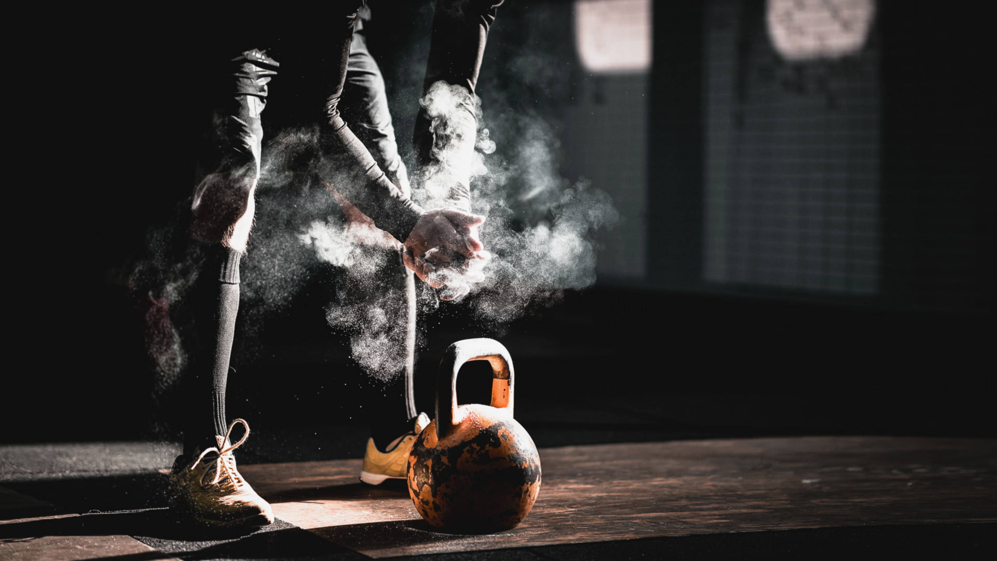 Motivation 桌布 壁紙 — 一個穿著運動服的人，在木地板上的一個壺鈴上方，戲劇性的聚光燈下拍手釋放出白色粉末。
