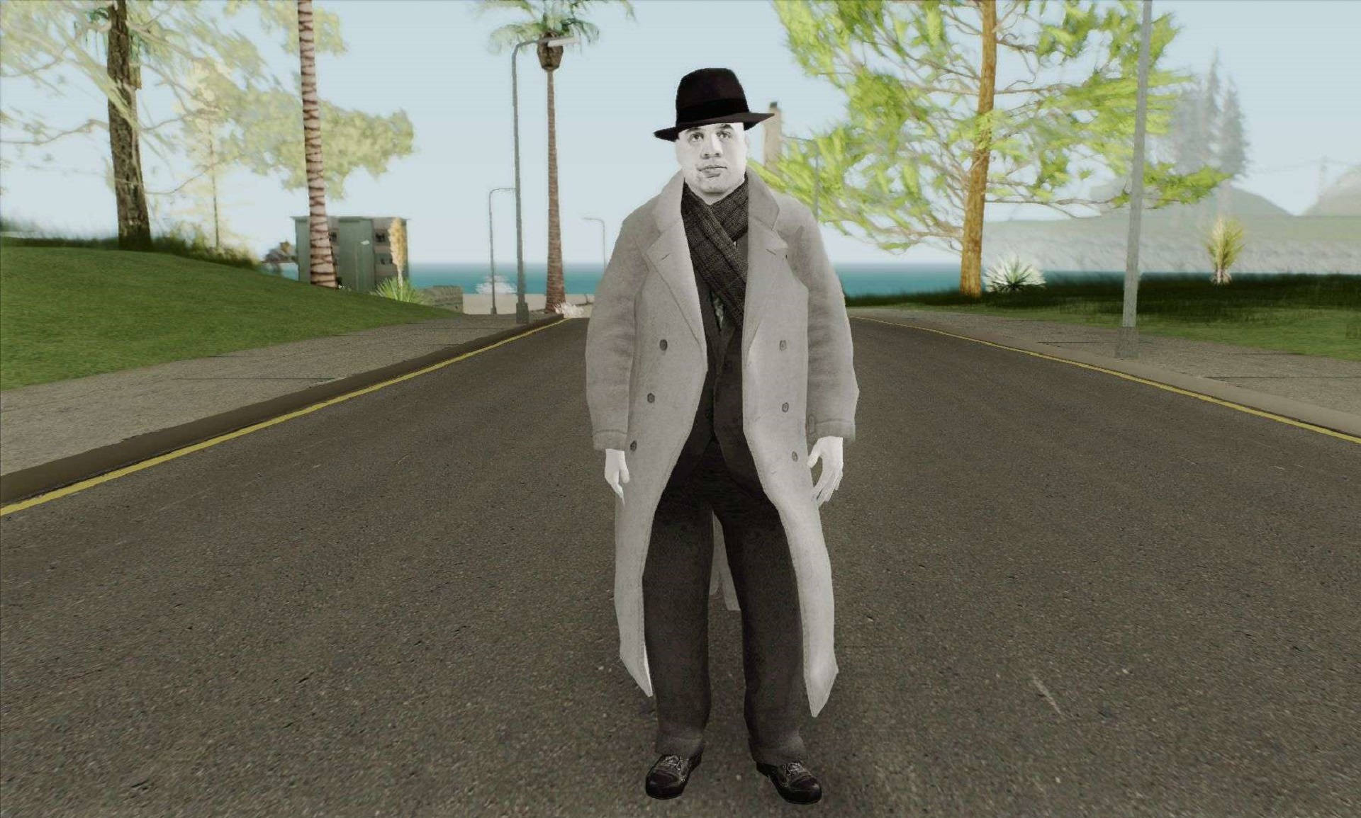 Capone 桌布 壁紙 — 一個穿著長外套和軟呢帽的男人站在一條沿海道路上，背景有棕櫚樹和海洋。
