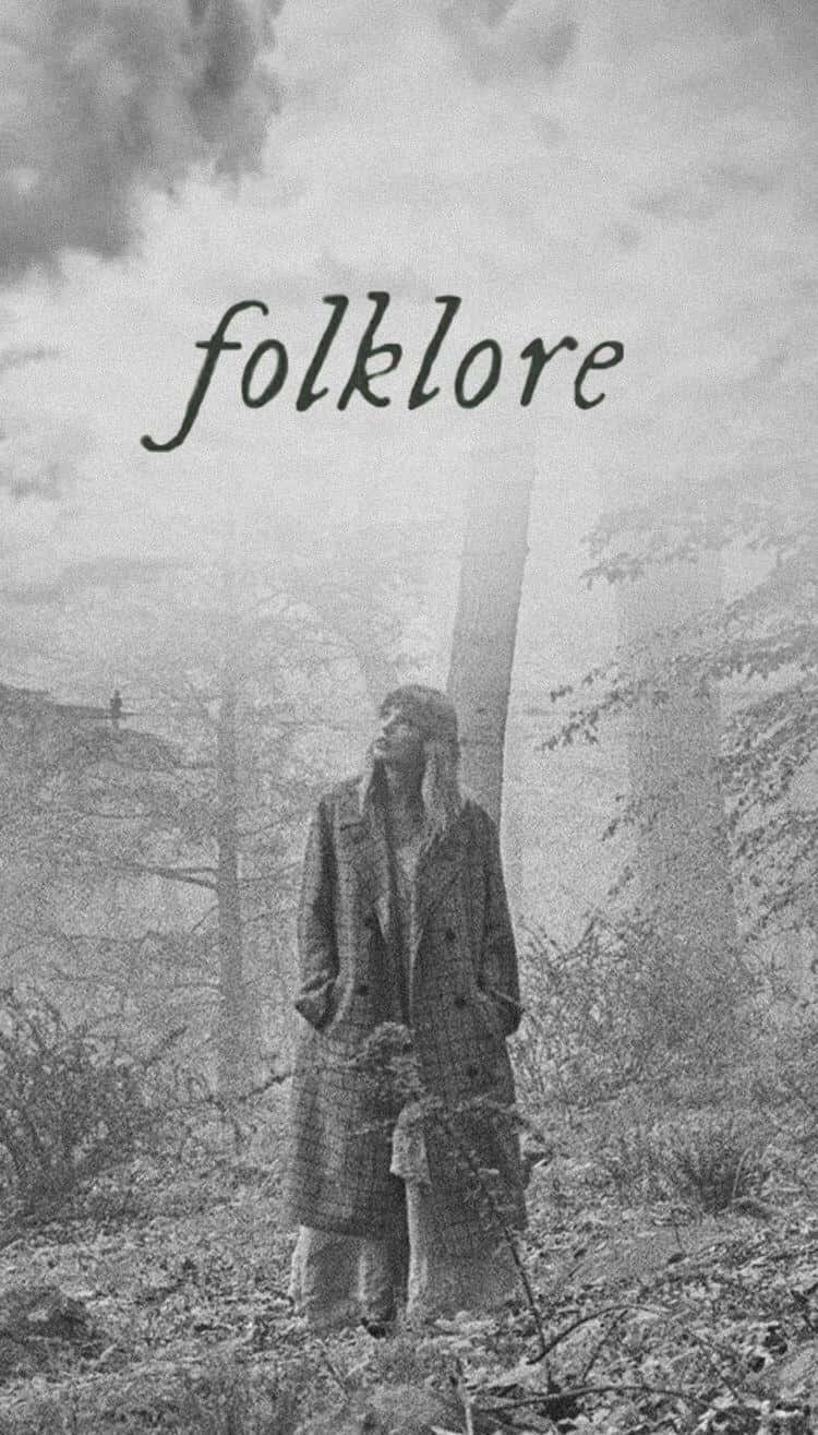 桌布 壁紙 — 一個穿著長外套的人站在霧氣瀰漫的森林中向上看，而「folklore」這個詞漂浮在他們上方。
