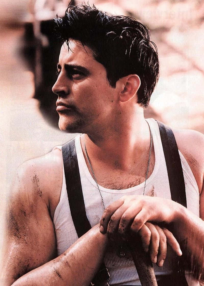 Matt Leblanc 桌布 壁紙 — 一個穿著骯髒白色背心和吊帶的男人，表情嚴肅地若有所思地看向一旁。