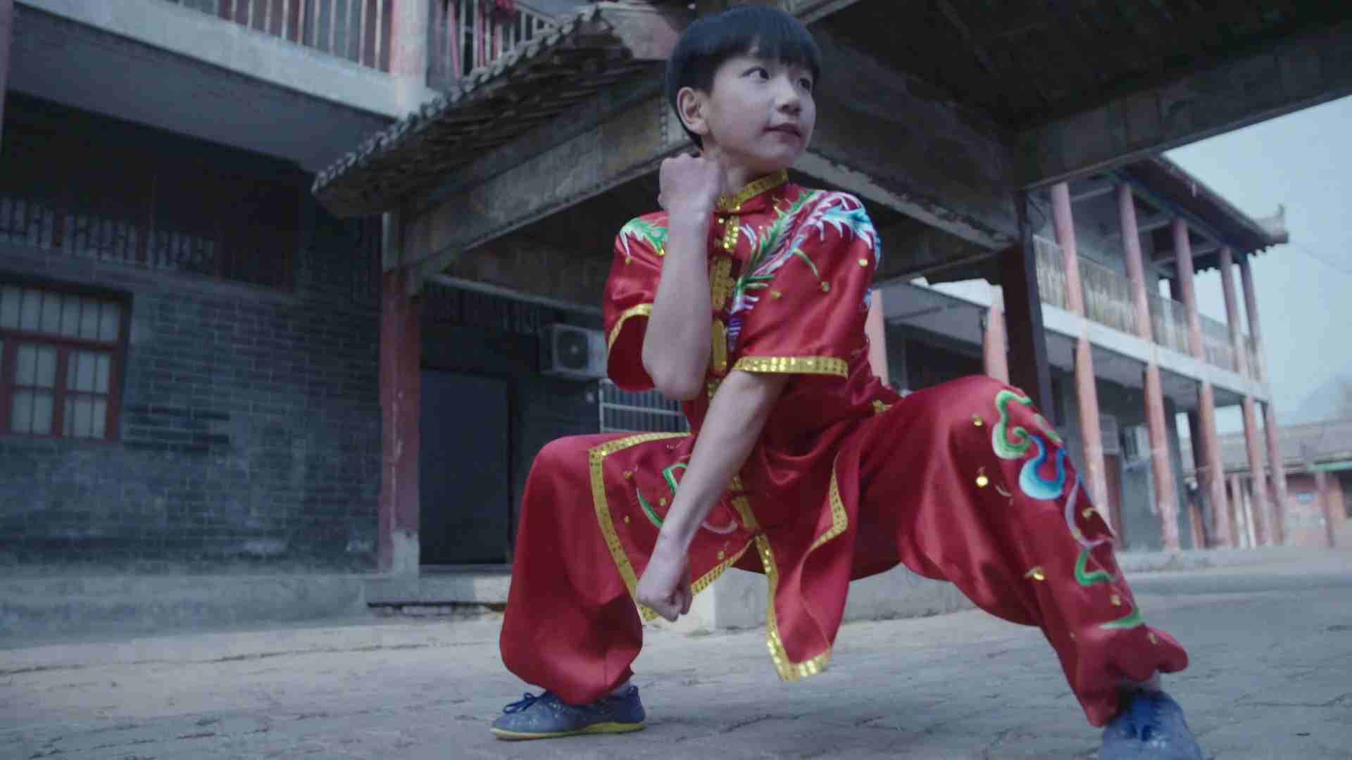Exercise 桌布 壁紙 — 一個穿著鮮紅色傳統服裝的小孩在風化的庭院地板上擺出武術姿勢。