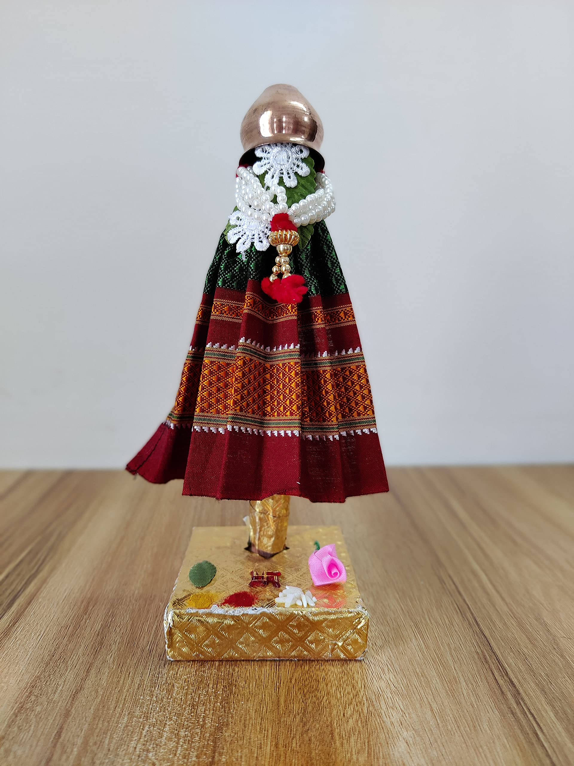 Gudi Padwa 桌布 壁紙 — 一個穿著鮮豔傳統服飾、帶有複雜圖案和銅頭盔的微型人偶，站在一個裝飾著小花朵的金色底座上。