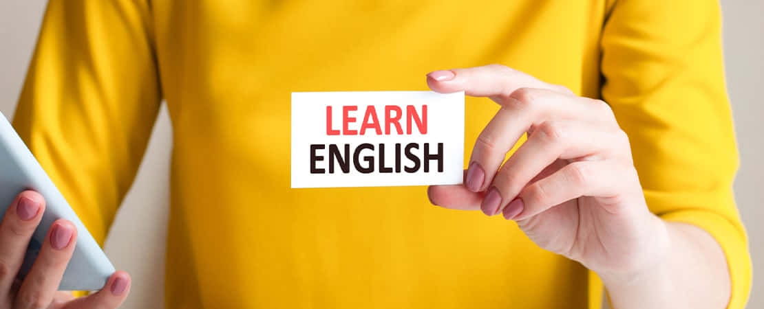 Learning 桌布 壁紙 — 一個穿著黃色襯衫的人拿著一張寫著「學習英語」的卡片，同時拿著平板電腦。