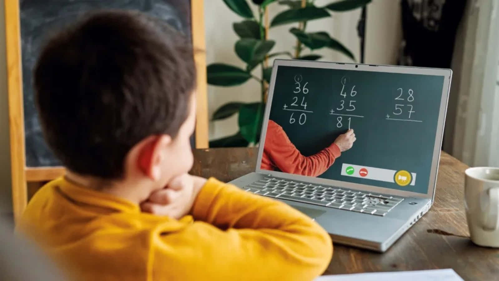 Learning 桌布 壁紙 — 一個穿著黃色襯衫的小男孩在舒適的家庭書房中看著老師在筆記型電腦螢幕上解決數學問題。