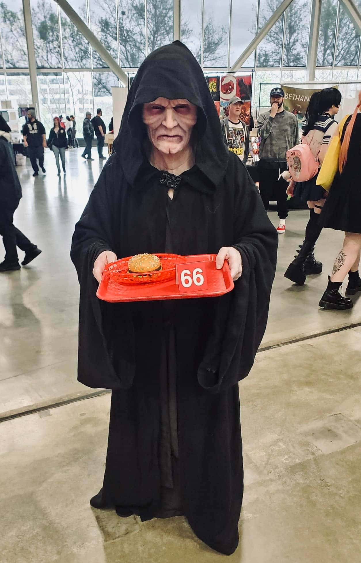 The Order 66 桌布 壁紙 — 一個穿著黑武士服裝的人在展會上拿著一個紅色托盤，上面有一個漢堡和數字66。