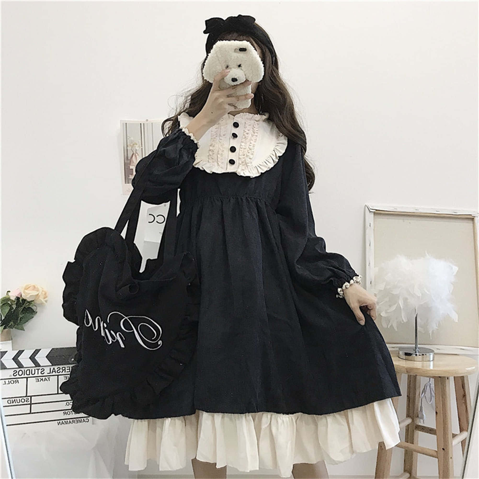 Lolita Fashion 桌布 壁紙 — 一個穿著黑白蘿莉塔連衣裙的人，在一個極簡風格的房間裡，抱著一隻毛茸茸的白狗，旁邊有一個木凳和羽毛燈。