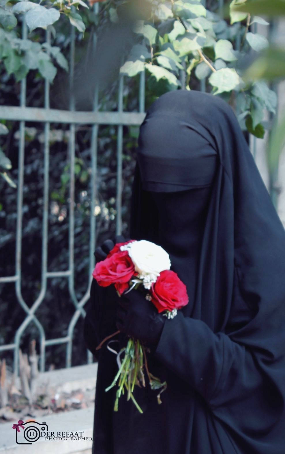 Woman 桌布 壁紙 — 一個穿著黑色尼卡布的人，手持一束紅白玫瑰，背景是綠色樹葉和金屬圍欄。