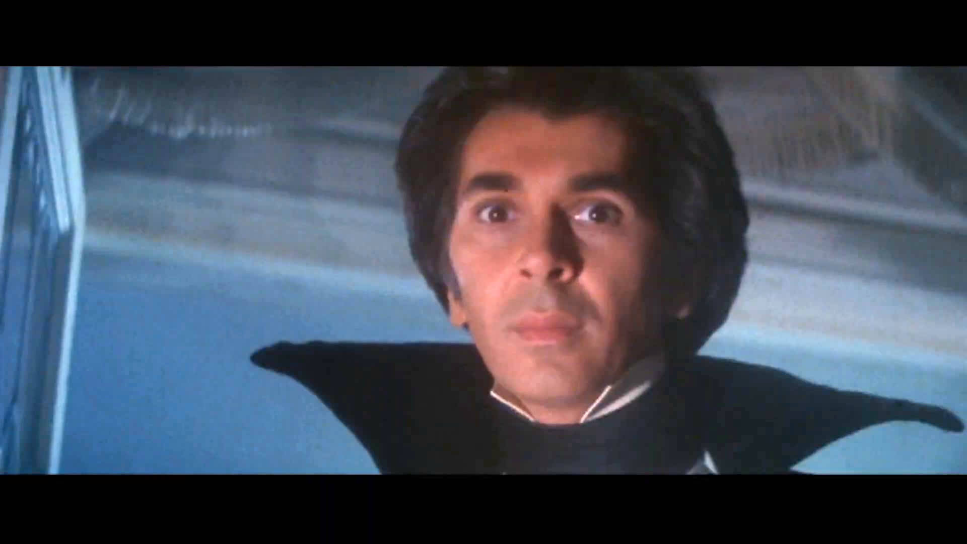 Celebrity 桌布 壁紙 — 一個穿著黑色斗篷的男人，在藍色調的背景前，睜大眼睛震驚地凝視著。
