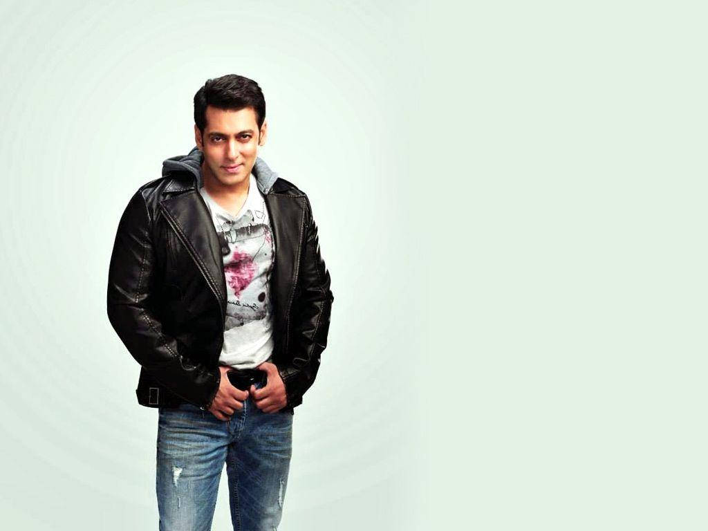 salman khan HD 桌布 壁紙 — 一個穿著黑色皮夾克和破洞牛仔褲的男人自信地站在柔和的漸變背景前。
