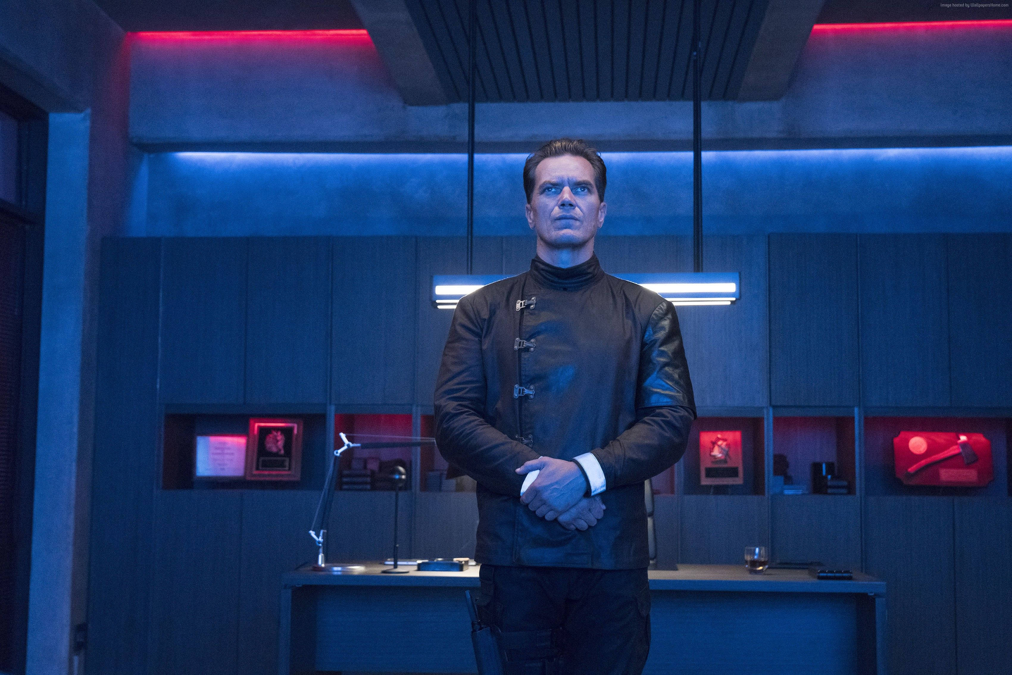 Entertainment 桌布 壁紙 — 一個穿著黑色皮夾克的男人站在一個燈光昏暗、充滿藍色和紅色霓虹燈的未來感辦公室。