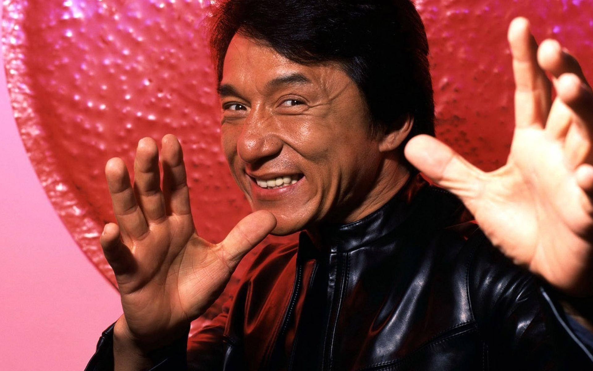 smiling 桌布 壁紙 — 一個穿著黑色皮夾克的開朗男人，在閃爍的粉紅色心形背景下熱情地揮手。