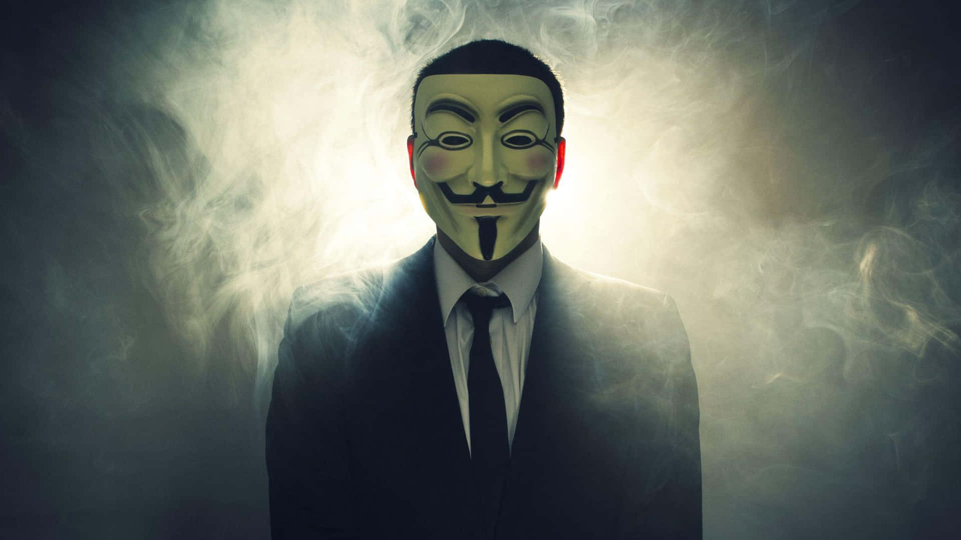 穿西裝的男人戴著蓋伊·福克斯面具，被煙霧環繞，背光照明。 — 匿名 GIF 壁紙
