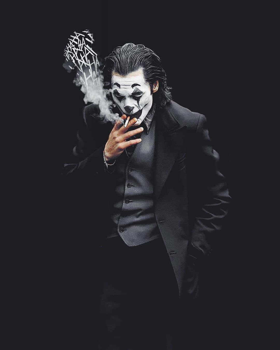 Dark Joker 桌布 壁紙 — 一個穿著黑色西裝的威脅性小丑在黑暗背景下抽煙，煙霧形成混亂的塗鴉。