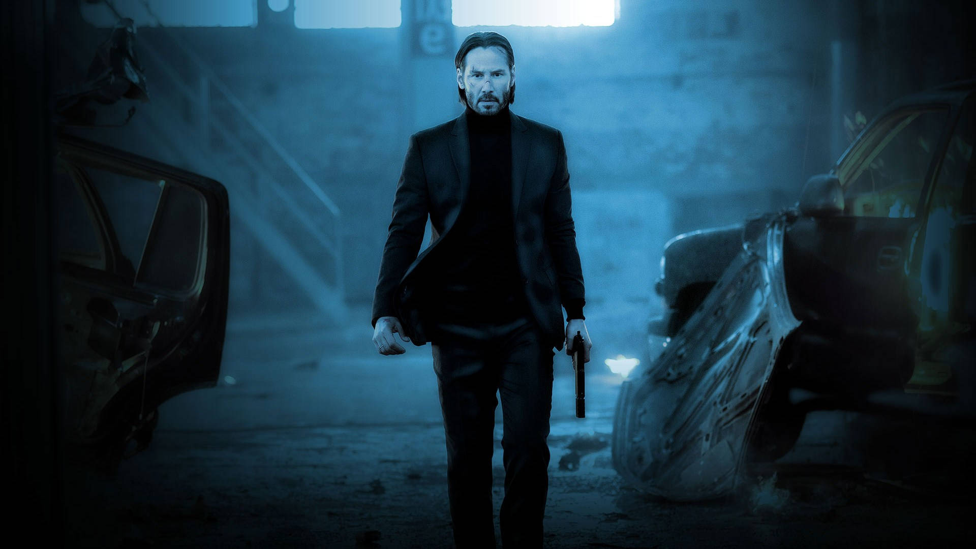 John Wick 桌布 壁紙 — 一個穿著黑色西裝的男人在昏暗的藍色燈光車庫中持槍行走，兩側有損毀的汽車。