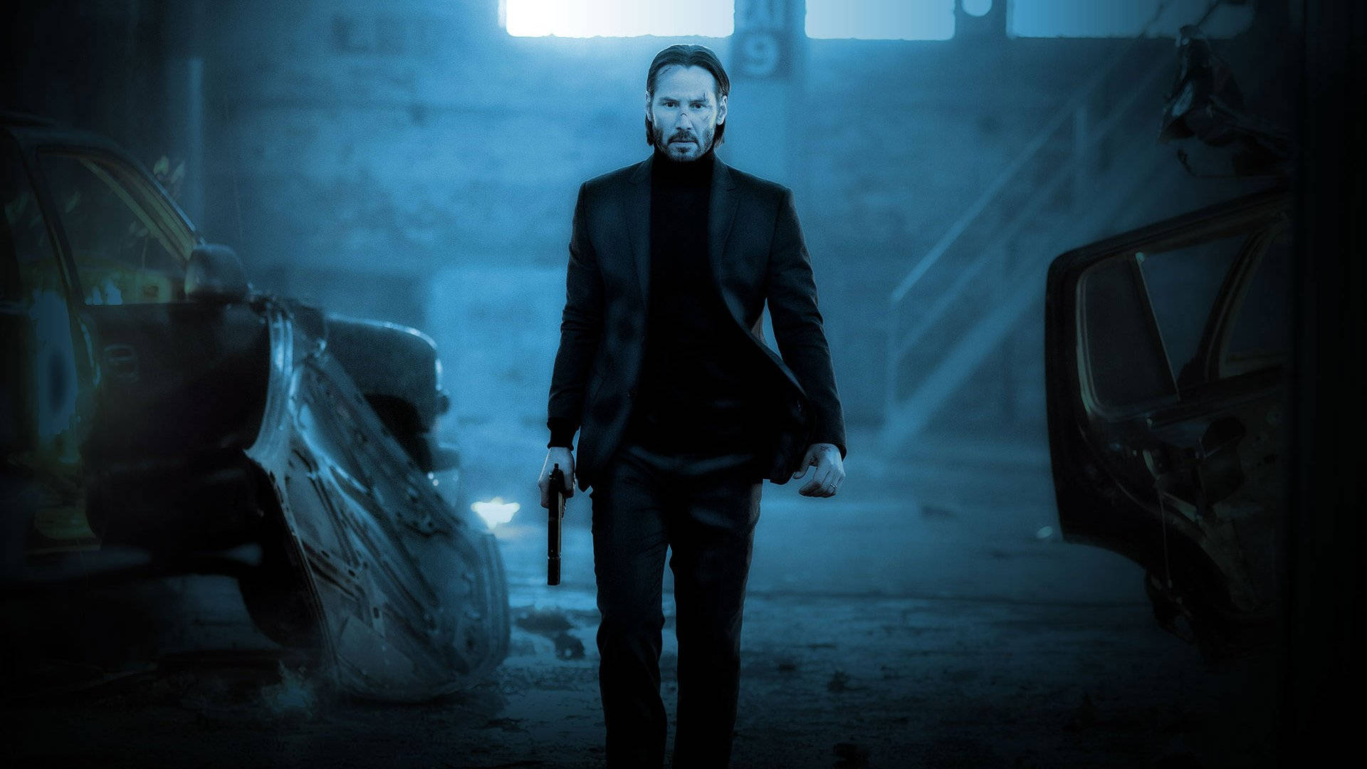 John Wick 桌布 壁紙 — 一個穿著黑色西裝的男人在昏暗的藍色燈光車庫中持槍行走，兩側有損毀的汽車。