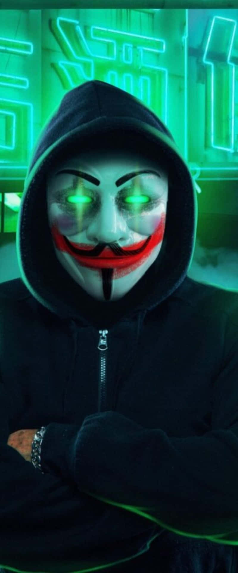  壁紙 — 一個穿著黑色連帽衫的人，在霓虹燈照亮的城市背景下戴著發光綠眼的蓋伊·福克斯面具。