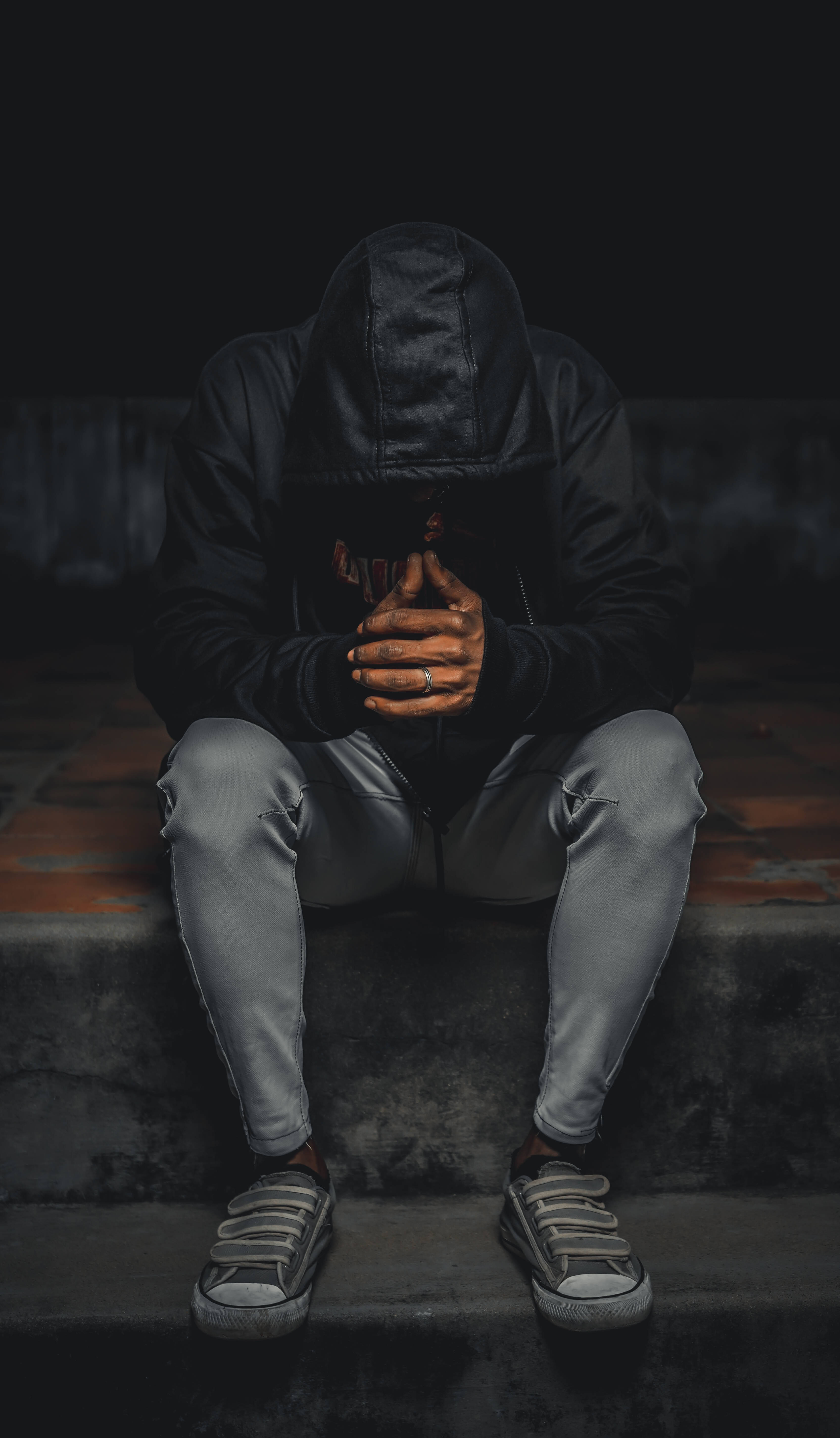 Depression Aesthetic 桌布 壁紙 — 一個穿著黑色連帽衫的人蜷縮在混凝土台階上，雙手掩面，處於陰暗憂鬱的環境中。