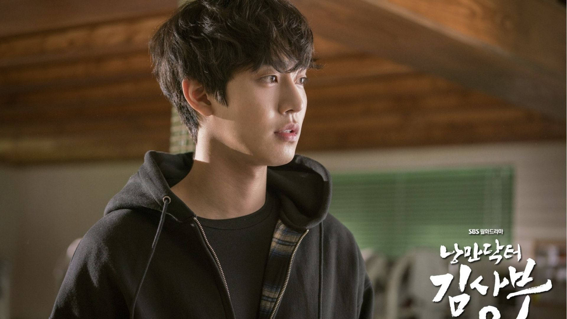 Ahn Hyo Seop 桌布 壁紙 — 一個穿著黑色連帽衫的年輕人在溫暖的木質房間裡若有所思地向上看。