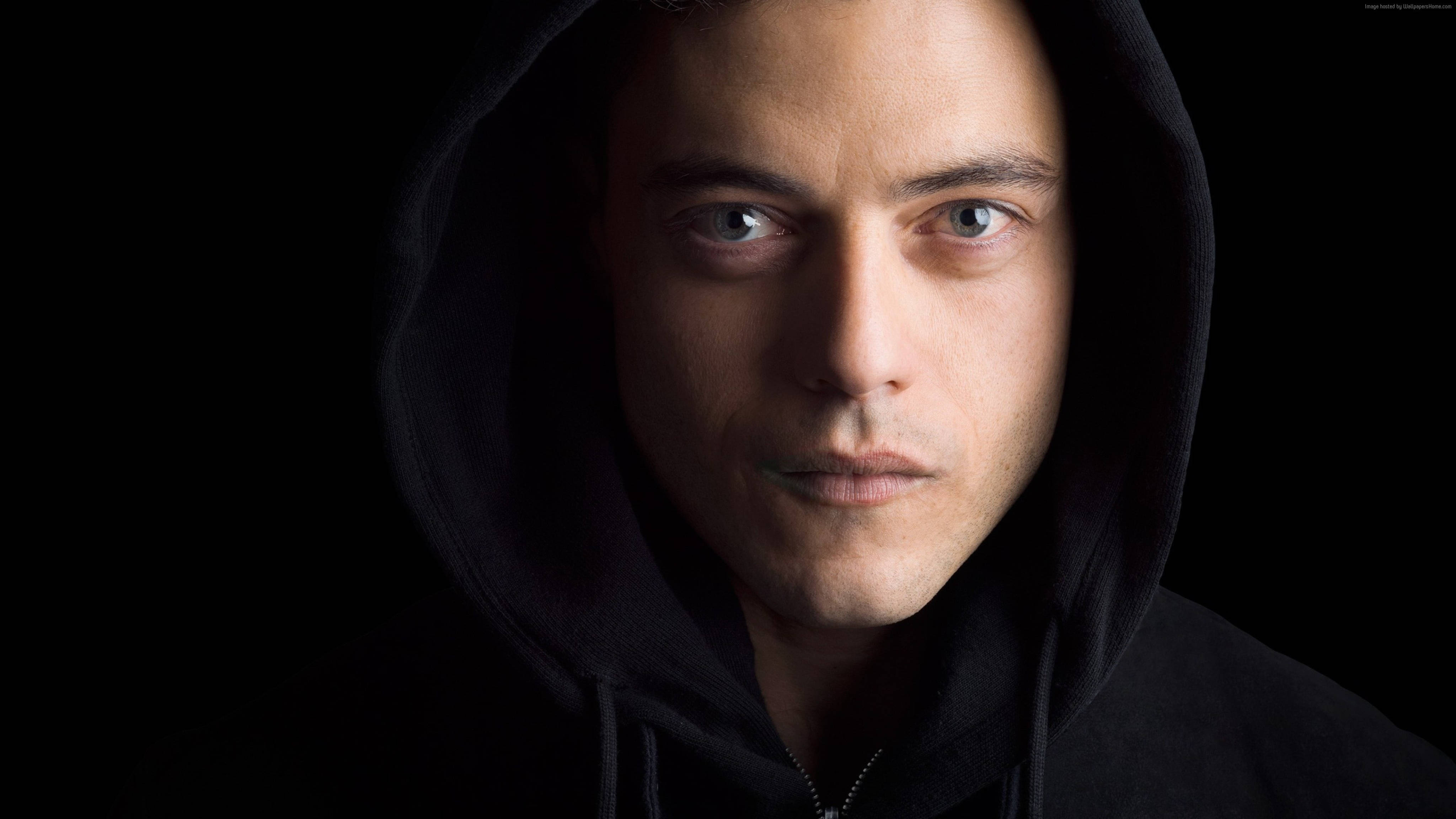 Mr Robot 桌布 壁紙 — 一個穿著黑色連帽衫的男人在黑暗背景下，戲劇性的燈光突出他的臉，他凝視著。