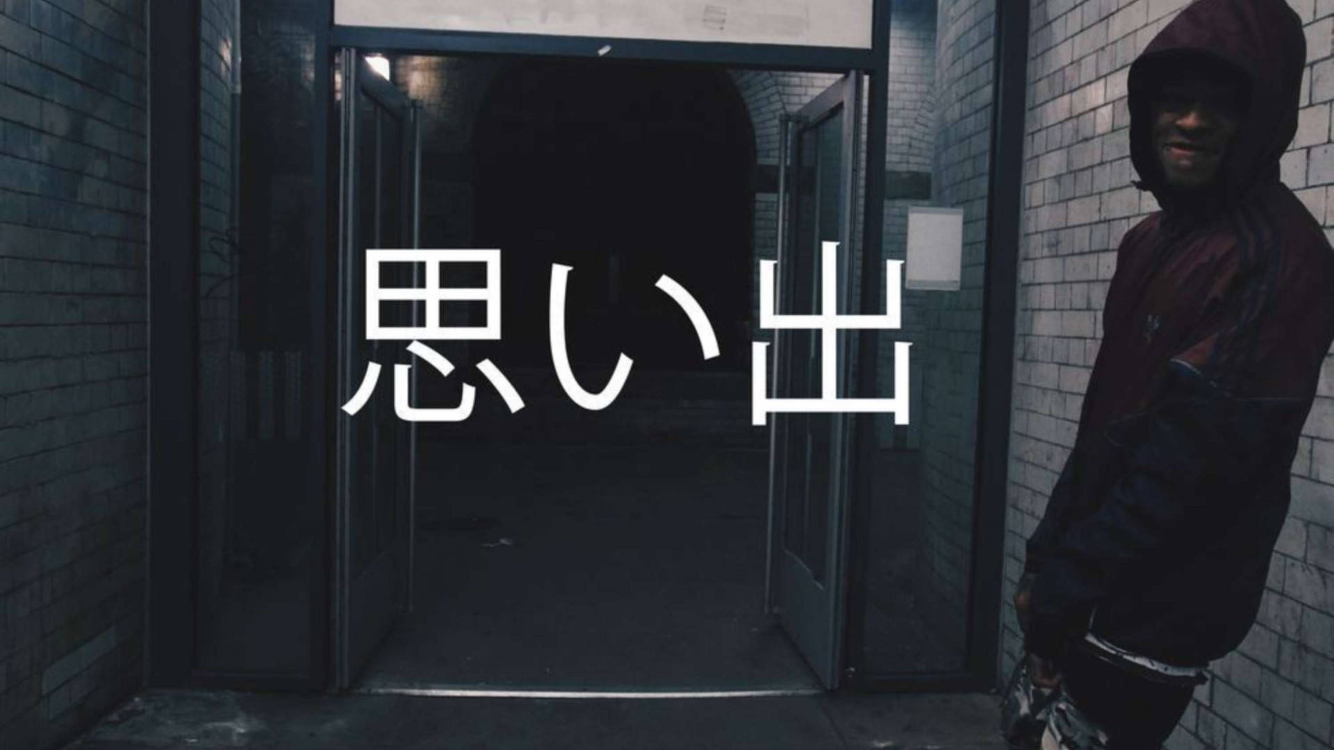 scarlxrd 桌布 壁紙 — 一個穿連帽衫的人靠著磚牆，旁邊是敞開的門口，上面覆蓋著大型白色日文字元。