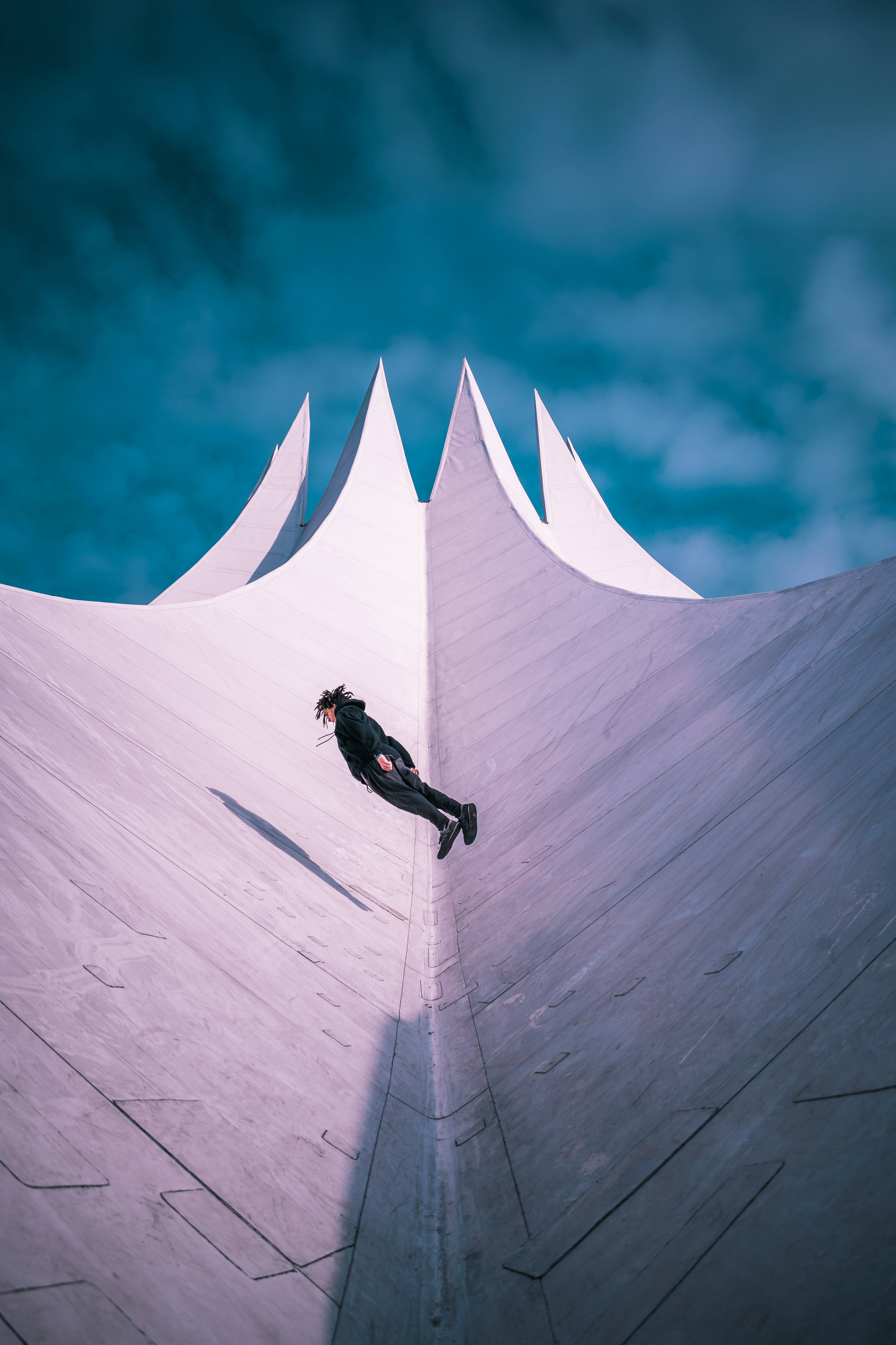 Parkour 桌布 壁紙 — 一個穿黑色衣服的人從一個巨大的白色帳篷頂端跳下，背景是憂鬱的藍綠色天空。