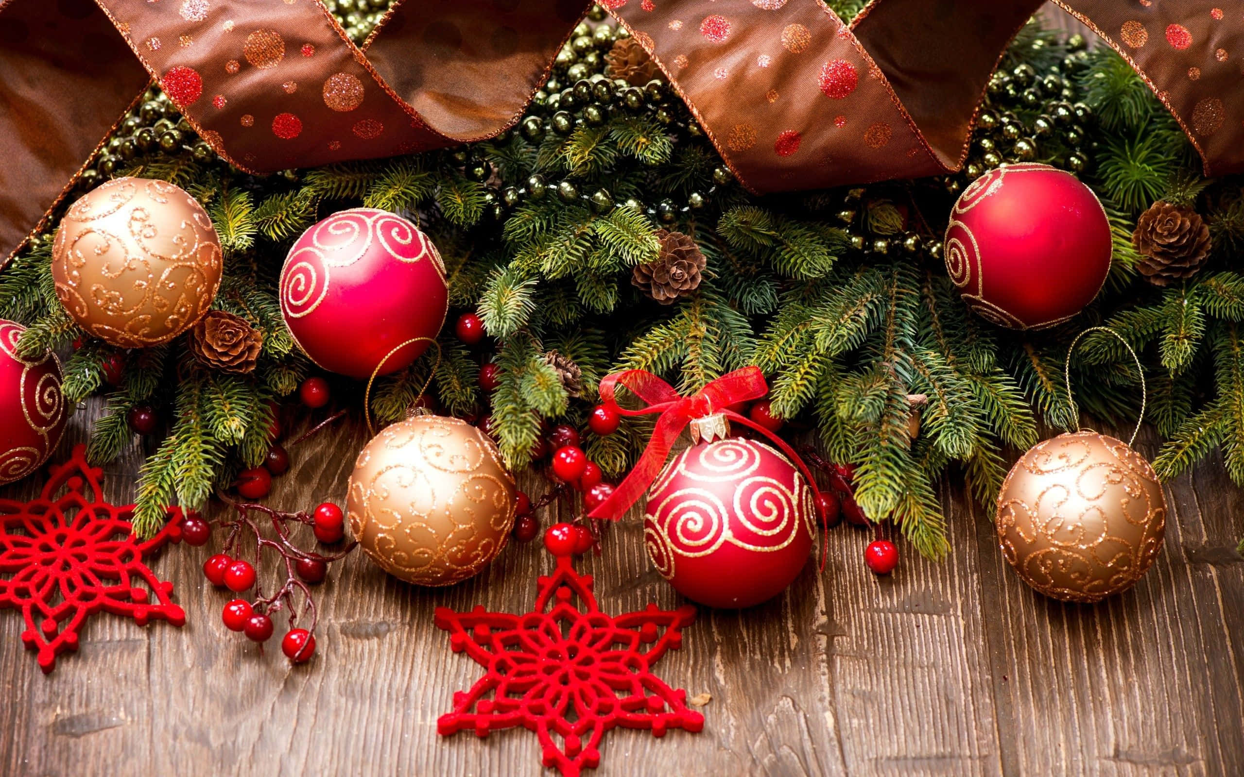 Christmas Ornament 桌布 壁紙 — 一個節日假期佈置，在質樸的木質表面上擺放紅色和金色的裝飾品、松樹枝、松果和紅色雪花。