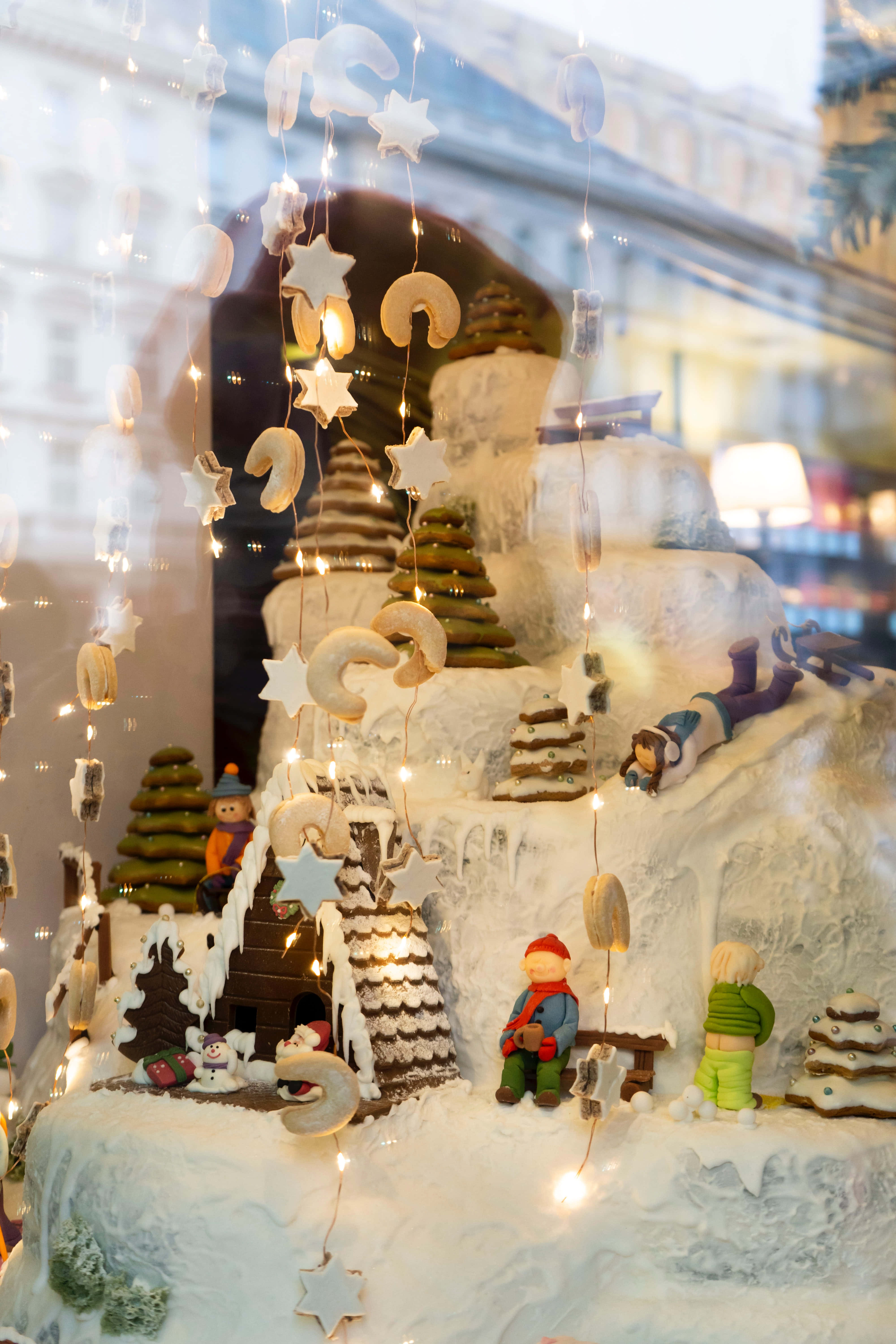 Christmas Scene 桌布 壁紙 — 一個節日冬季仙境立體模型，有白雪覆蓋的微型房屋、樹木和人物，由燈串照亮。