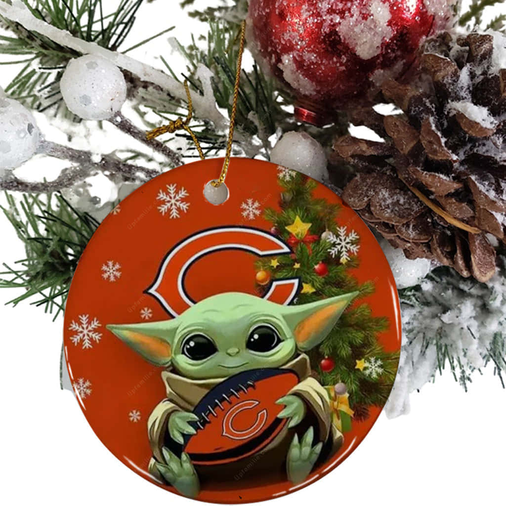 Baby Yoda Christmas 桌布 壁紙 — 一個節日圓形裝飾， featuring 尤達寶寶手持芝加哥熊隊美式足球，被雪花和聖誕樹環繞，背景是白雪覆蓋的松樹。