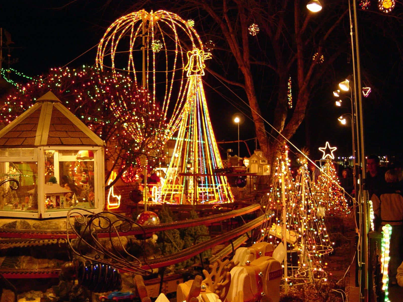 Christmas Light 桌布 壁紙 — 一個節日夜晚場景，閃爍的聖誕燈飾裝飾著樹木和一個巨大的摩天輪。