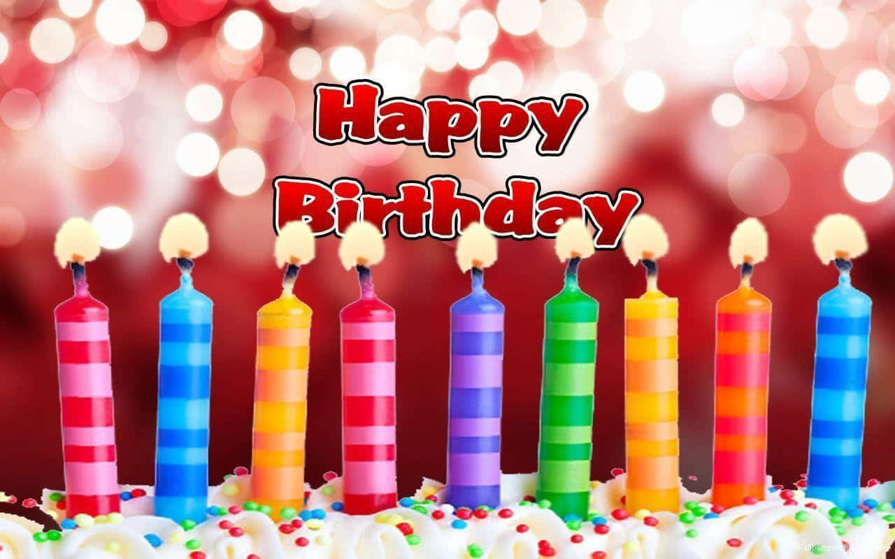 生日快樂 桌布 壁紙 — 一個節日生日蛋糕，裝飾著彩色條紋蠟燭和糖粒，背景是發光的紅色散景。