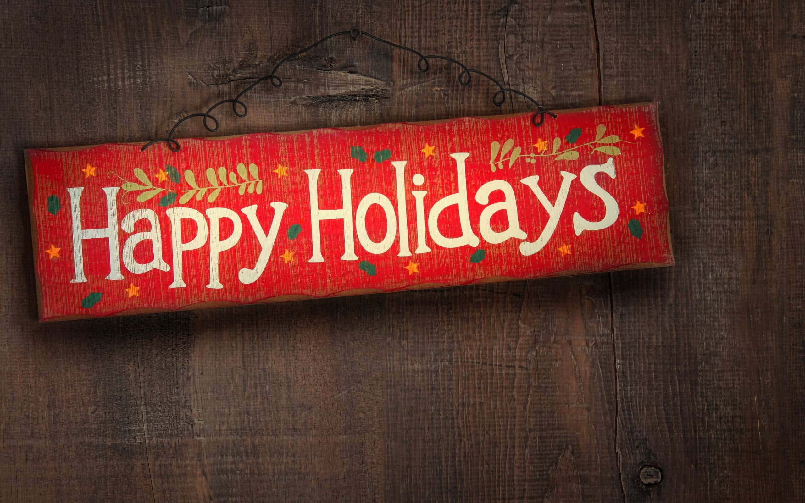 節日 桌布 壁紙 — 一個節日紅色木牌，上面有白色草書 'Happy Holidays' 和綠色星星，掛在深色質樸的木牆上。