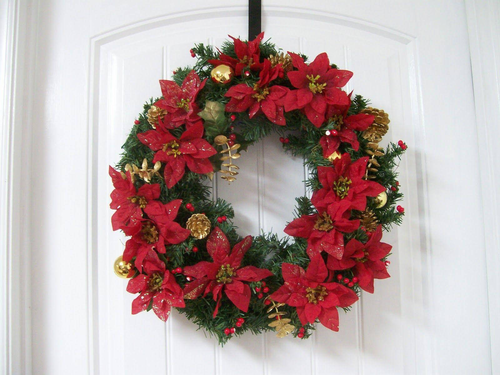 Wreath 桌布 壁紙 — 一個節日紅色聖誕紅花環，飾有金色裝飾品和松果，掛在白色門上。