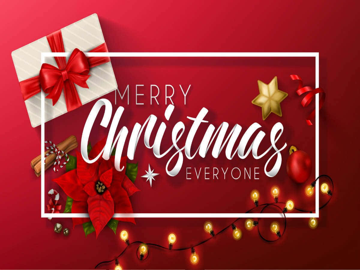 Greetings 桌布 壁紙 — 一個節日紅色背景，裝飾著白色禮物盒、紅色蝴蝶結、聖誕紅、肉桂棒和閃爍的燈串，圍繞著白色框架的「祝大家聖誕快樂」文字。