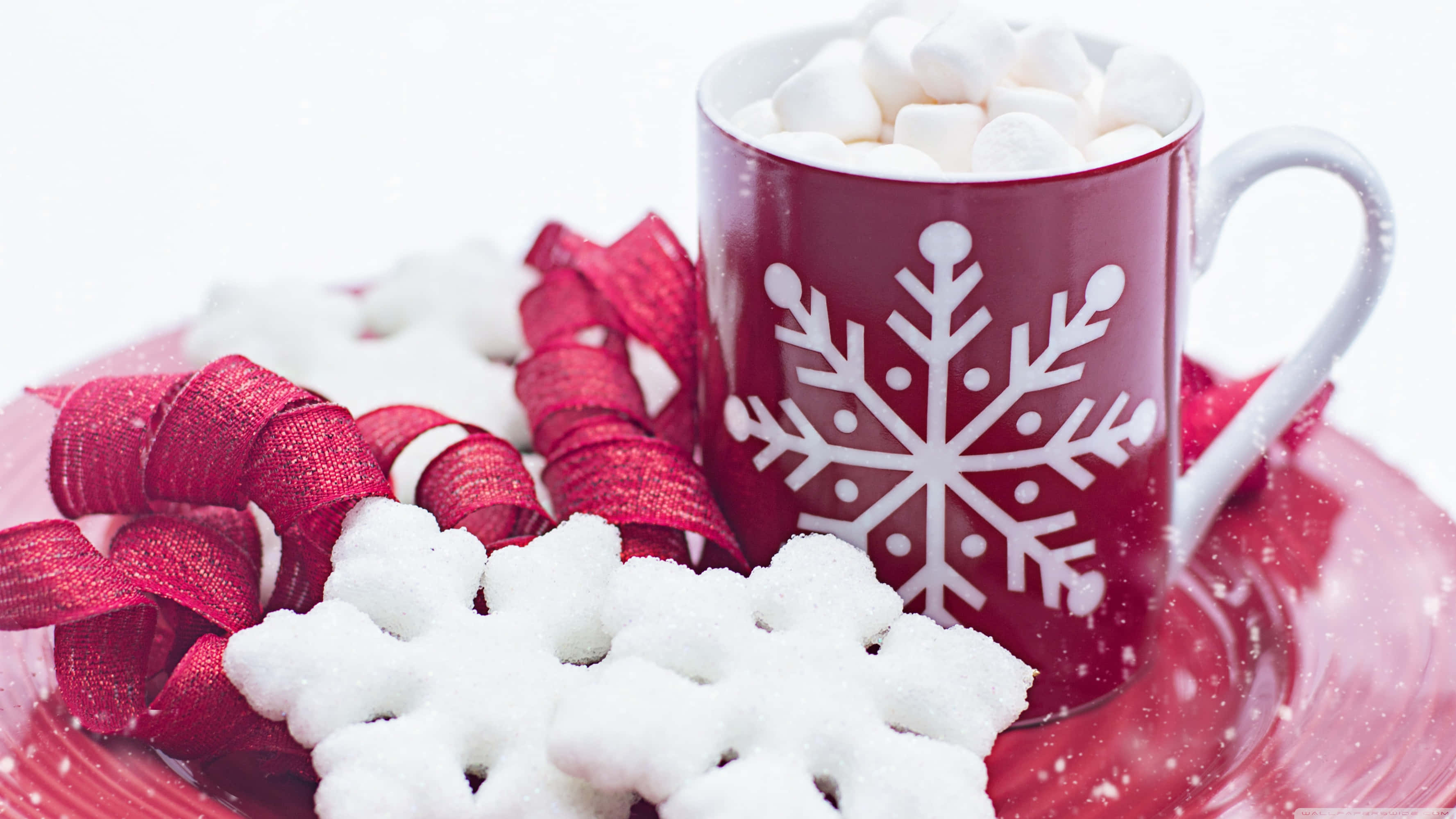Hot Chocolate 桌布 壁紙 — 一個節日紅色馬克杯裝滿熱可可和棉花糖，旁邊放著雪花餅乾和紅色絲帶，放在相配的盤子上。