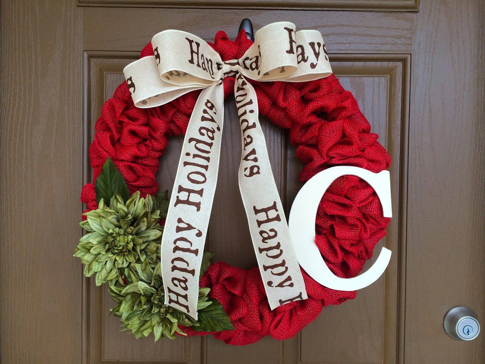 Wreath 桌布 壁紙 — 一個節日紅麻花環，帶有奶油色蝴蝶結，上面寫著「Happy Holidays」，還有一個大大的白色字母C，裝飾著木製前門。