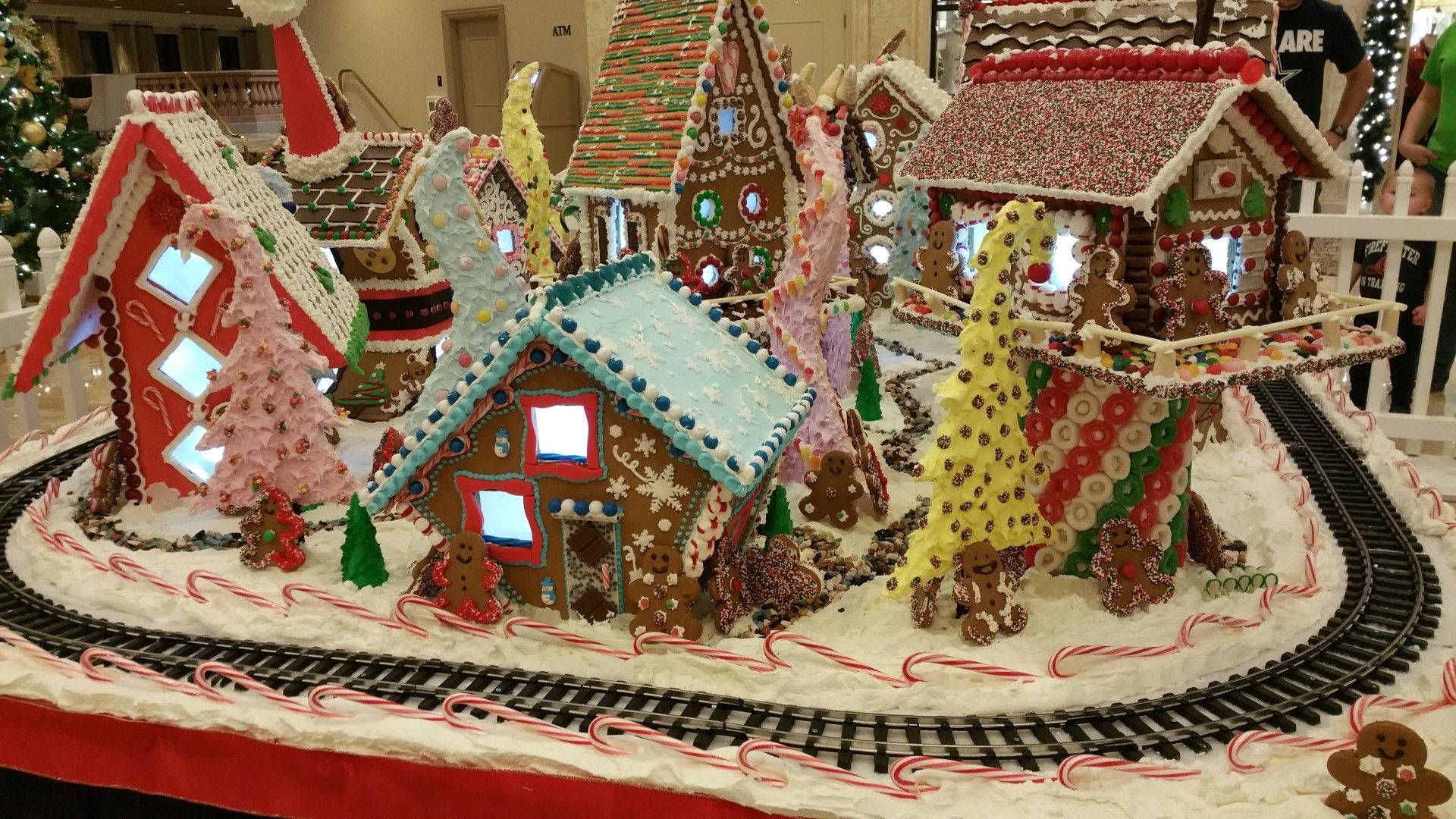 Gingerbread House 桌布 壁紙 — 一個節日薑餅村莊，有糖果屋、雪樹和火車軌道，全部用彩色糖霜和糖粒裝飾。