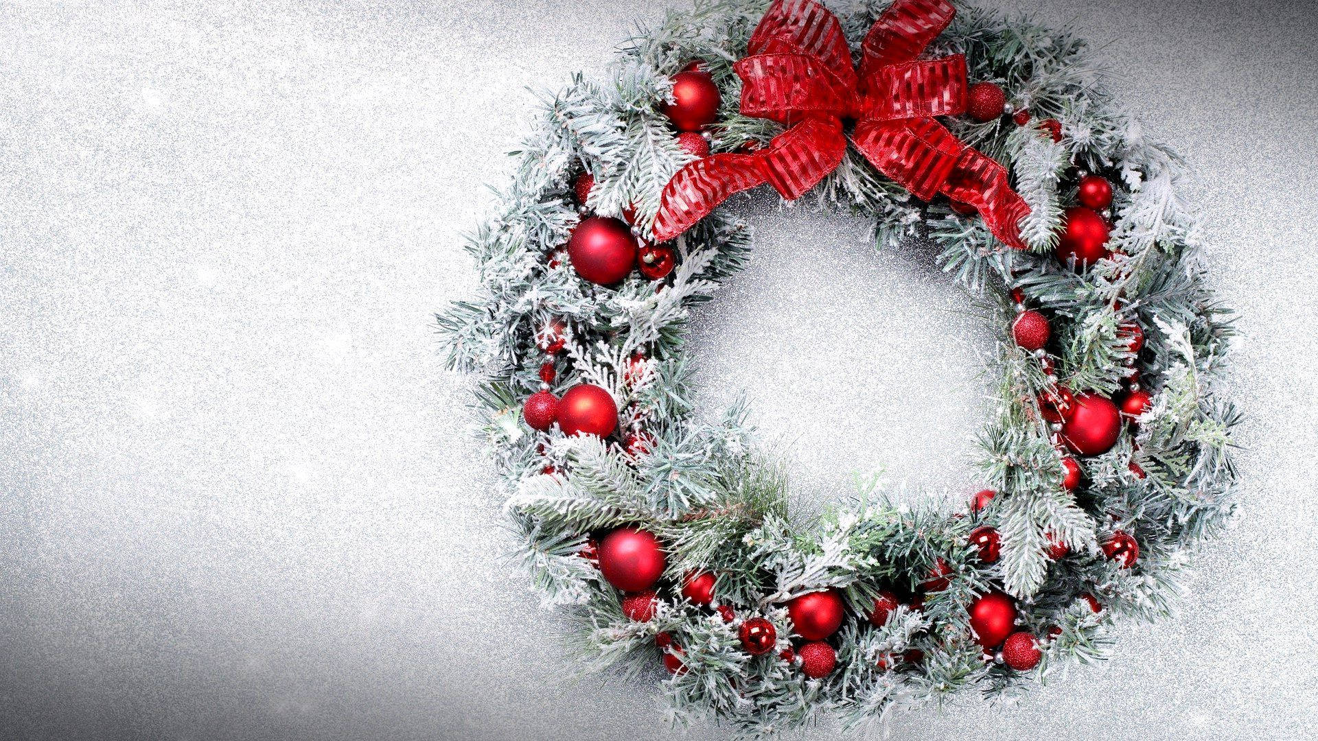 Wreath 桌布 壁紙 — 一個節日雪霜覆蓋的聖誕花環，裝飾著紅色飾品和一個大紅色蝴蝶結，背景是柔和的銀色。