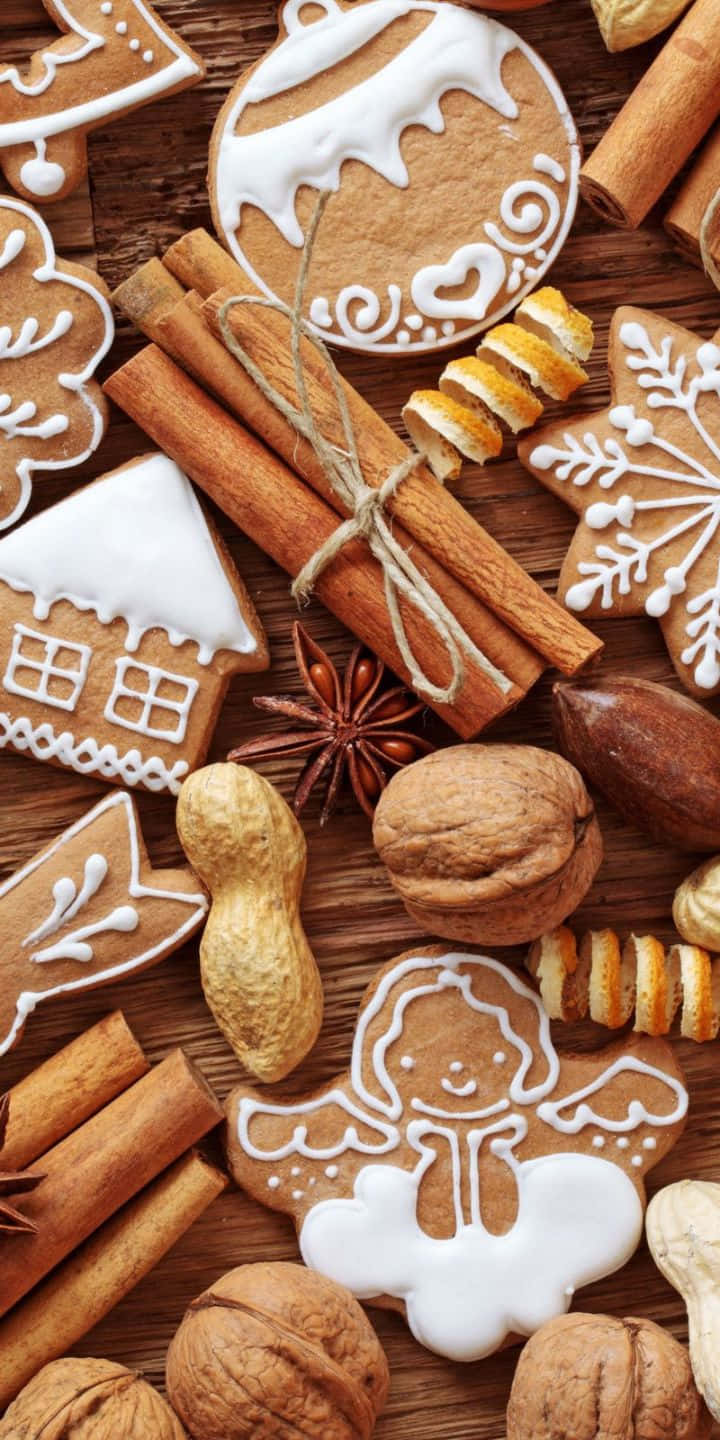 Pastry 桌布 壁紙 — 一個節日風格的平鋪擺設，包括用白色糖霜裝飾的薑餅餅乾，以及肉桂棒、堅果和八角，放在質樸的木質表面上。
