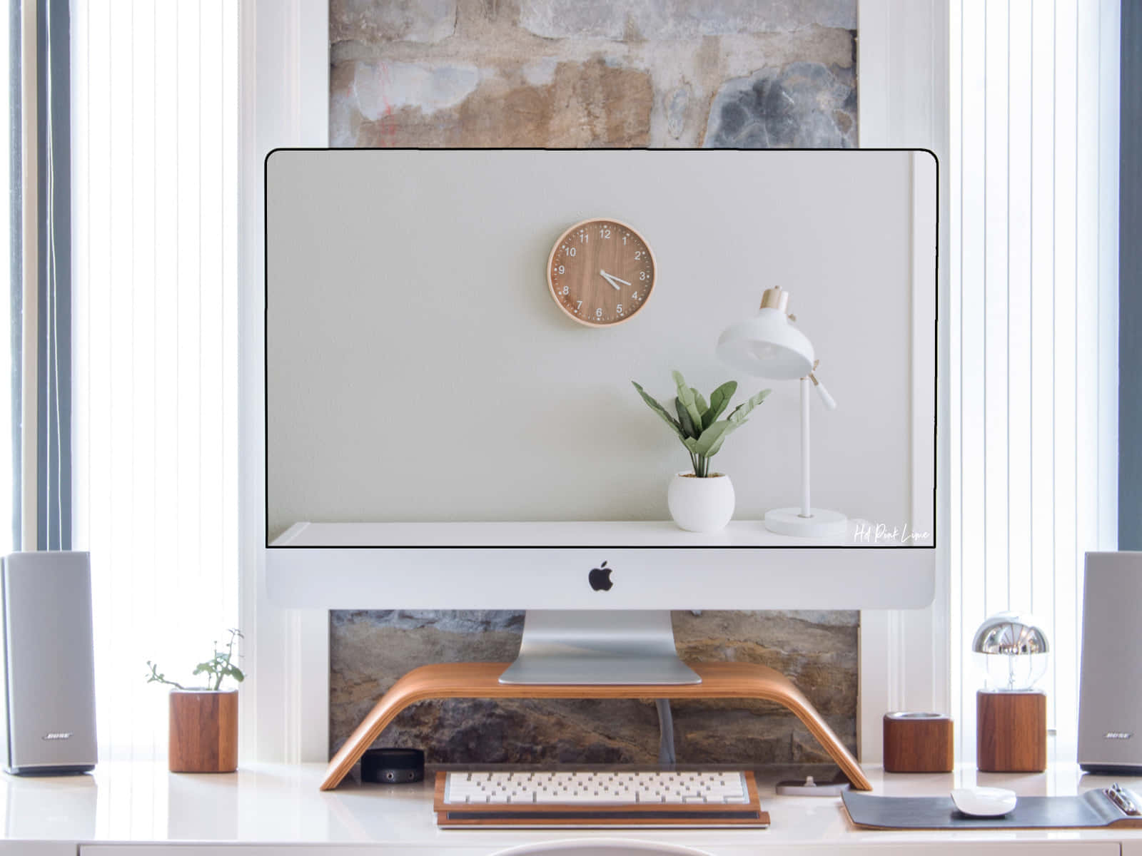 白色美學動圖 桌布 壁紙 — 一個簡約家居辦公室設置，白色iMac放在木製支架上，兩側有揚聲器和小型盆栽植物靠近窗戶。