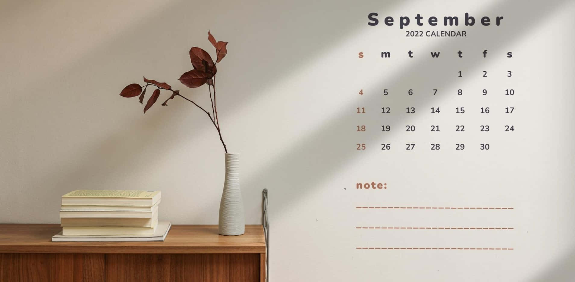 September 桌布 壁紙 — 一個簡約的2022年9月月曆掛在牆上，旁邊是一個木架，上面放著書本和一個插有乾葉的花瓶。
