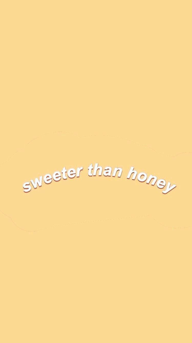 Pastel Yellow Aesthetic 桌布 壁紙 — 一個簡約的淺黃色背景，上面有白色彎曲文字寫著「sweeter than honey」。