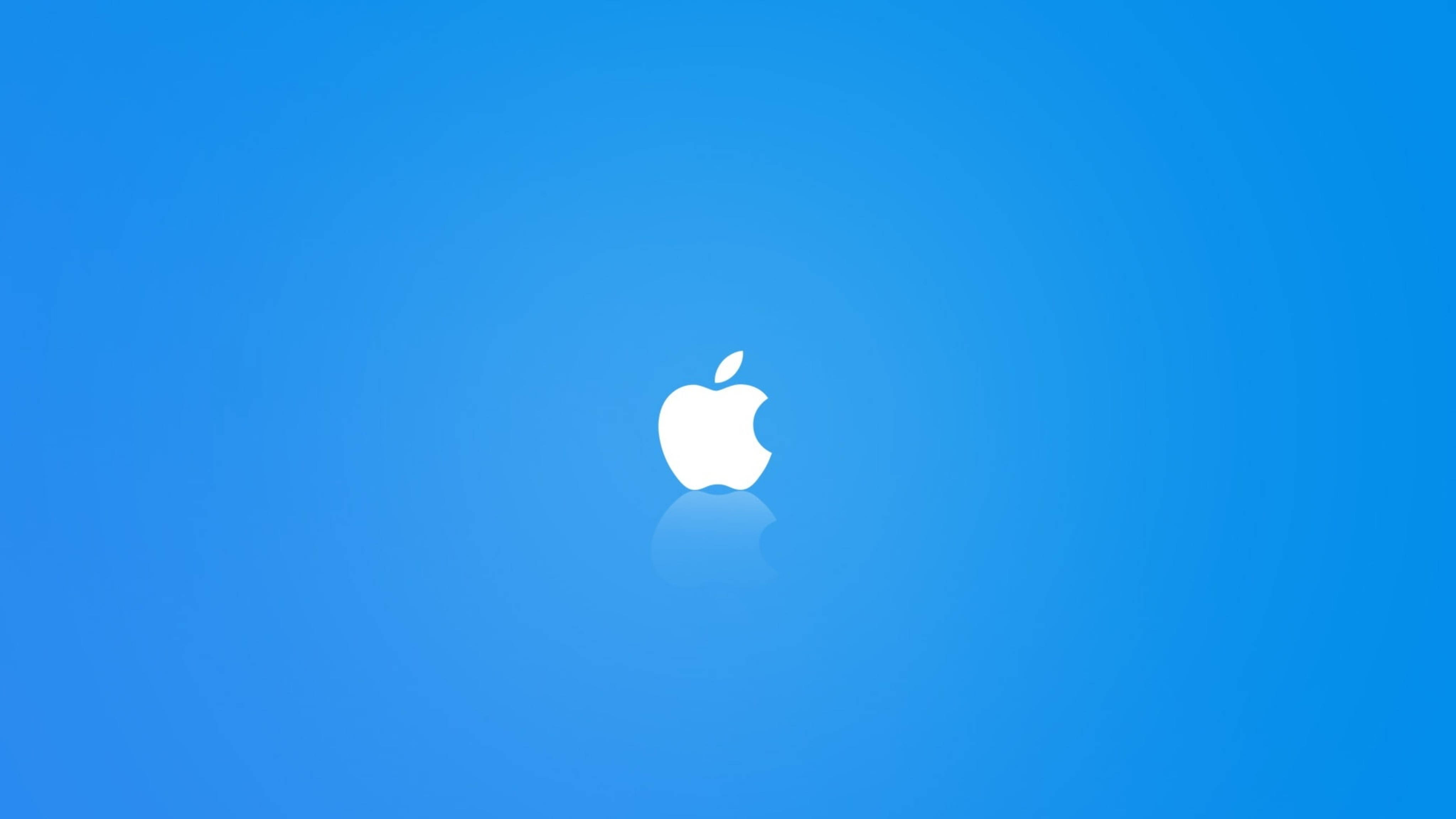 Apple 4K Ultra HD 桌布 壁紙 — 一個簡約的白色Apple標誌，居中在漸變藍色背景上，帶有微妙的倒影。